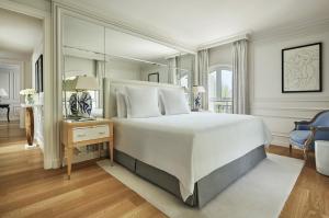a bedroom with a large white bed with a mirror at Grand-Hôtel du Cap-Ferrat, A Four Seasons Hotel in Saint-Jean-Cap-Ferrat