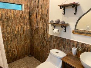 a bathroom with a toilet and a sink and a mirror at Boutique Rooms at La Junta in Dominical