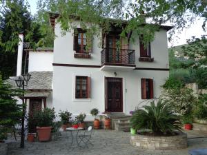 a white house with red windows and a courtyard at Archontiko Stafylopati in Makrinitsa