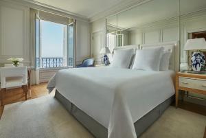 a bedroom with a large white bed and a desk at Grand-Hôtel du Cap-Ferrat, A Four Seasons Hotel in Saint-Jean-Cap-Ferrat