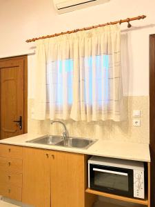 een keuken met een wastafel en een magnetron bij Ambela House Soroni in Soroni