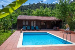 a swimming pool in front of a house at Quinta da Mal-disposta, cabin lodge Countryhouse in Resende