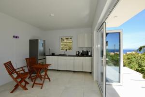 cocina con armarios blancos, mesa y sillas en Beach House,Villa Santirome/Free Wifi,Parking en Westpunt