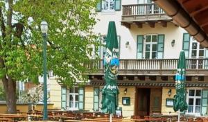 un edificio con sombrillas verdes delante en Gasthaus Franz Inselkammer, en Höhenkirchen-Siegertsbrunn