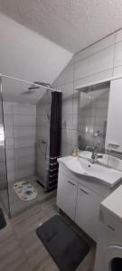 Baño blanco con lavabo y espejo en Apartman Karolina, en Rudanovac