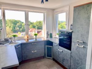 a kitchen with gray cabinets and windows and a sink at Laudervale Penthouse Loch Lomond in Balloch