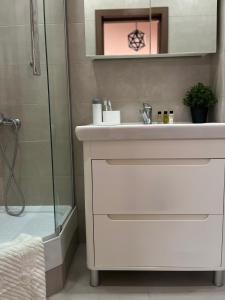 een badkamer met een witte wastafel en een douche bij Жилой комплекс Ирина in Pavlodar