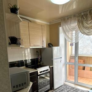 a kitchen with a white refrigerator and a window at Район Юбилейный - Боулинг in Karagandy