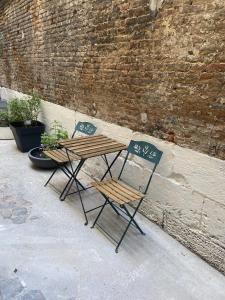 2 sedie e un tavolo in legno accanto a un muro di mattoni di CosyRouen Bali Spa Hamman a Rouen