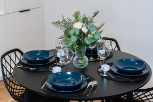 a black table with blue plates and a vase of flowers at Modern&Cozy Garbary Apartment with Parking and Balcony by Renters in Poznań