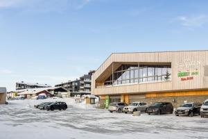 a parking lot with cars parked in front of a building at Leilighet med panoramautsikt Sjusjøen Innendørs parkering in Sjusjøen