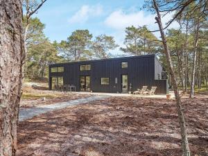 a black house in the middle of a forest at Holiday home Nexø XLI in Vester Sømarken