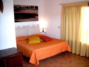 een slaapkamer met een bed met een oranje sprei bij Casa Belvedere -tranquillità tra bosco e ulivi- in Riparbella