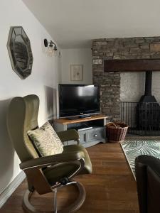 a living room with a chair and a flat screen tv at Cilhendre Holiday Cottages - The Dairy in Swansea