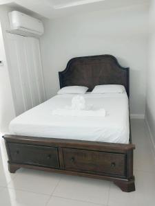 a bed with a wooden frame and white sheets at Impeccable 2-BR Apartment-Ornella Villa at Bayfront Villa in Portmore