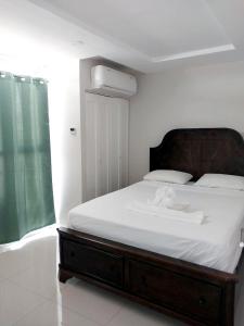 a bedroom with a large bed with a wooden headboard at Impeccable 2-BR Apartment-Ornella Villa at Bayfront Villa in Portmore