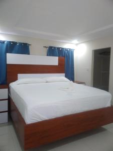 a bedroom with a large bed with blue curtains at Impeccable 2-BR Apartment-Ornella Villa at Bayfront Villa in Portmore