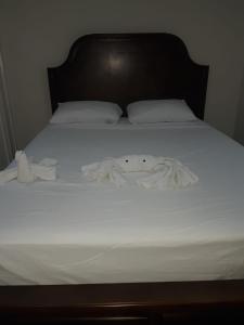 uma cama com lençóis brancos e toalhas em Impeccable 2-BR Apartment-Ornella Villa at Bayfront Villa em Portmore