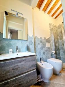 bagno con lavandino, servizi igienici e specchio di Serra di mare casa con giardino a Livorno