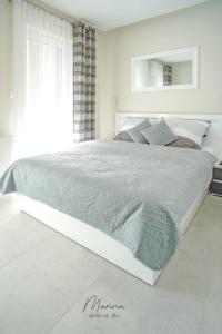 a white bedroom with a large white bed in a room at Marina Apartament 11 Iława - z prywatnym miejscem parkingowym w podziemnym garażu in Iława