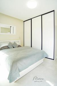 a white bedroom with a large bed with glass doors at Marina Apartament 11 Iława - z prywatnym miejscem parkingowym w podziemnym garażu in Iława