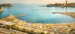 une piscine avec parasols et chaises longues sur une plage dans l'établissement Apartmani Luka, à Rab
