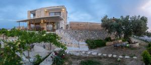 una casa con una pared de piedra y escaleras delante en Rafaela holiday home, en Pitsidia