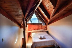 a small attic room with a bed with a window at LA PONDEROSA Apart Hotel in San Carlos de Bariloche