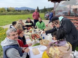 un grupo de personas sentadas alrededor de una mesa comiendo comida en Transylvania Apartments en Borzont