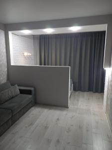 ein Wohnzimmer mit einem Sofa und einem großen Fenster in der Unterkunft Квартира в центре, новострой in Tschernihiw