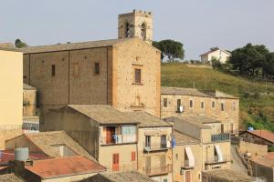 um grupo de edifícios com uma torre de relógio numa colina em Al Borghetto em Piazza Armerina