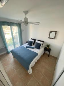 a bedroom with a bed with blue sheets and a fan at Marina 26 in Aigues-Mortes