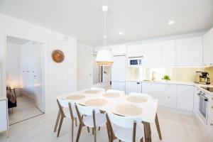a white kitchen with a white table and chairs at Apartment Tuomenkartano C4 iso huoneisto saunalla Kalajoki in Kalajoki