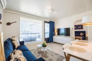 ein Wohnzimmer mit einem blauen Sofa und einem TV in der Unterkunft Apartment Tuomenkartano C4 iso huoneisto saunalla Kalajoki in Kalajoki