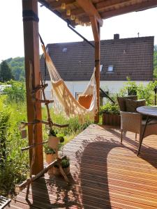 a hammock on a deck with a table and chairs at Ferienwohnung Waldschloss in Eppenbrunn