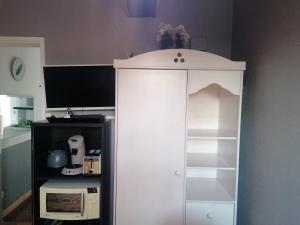 - une armoire blanche dans la cuisine équipée d'un four micro-ondes dans l'établissement Charmant Appartement 10mn Rouen, à Franqueville-Saint-Pierre