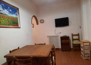 een woonkamer met een tafel en een tv aan de muur bij La Cantinetta di Barberino in Greve in Chianti