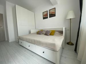 a white bedroom with a bed and a lamp at Orhideea Central Apartments in Bucharest