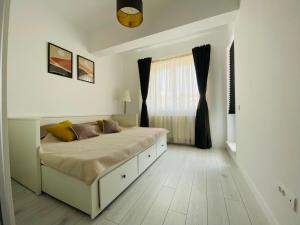 a white bedroom with a large bed and a window at Orhideea Central Apartments in Bucharest