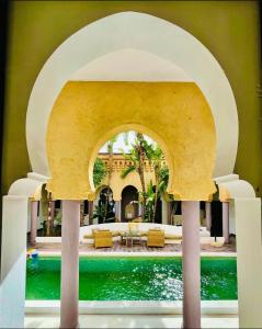 einen Torbogen über einem Wasserpool in einem Haus in der Unterkunft Les jardins d isis in Marrakesch