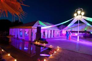 ein Festzelt leuchtet nachts mit lila und grünen Lichtern in der Unterkunft Les jardins d isis in Marrakesch