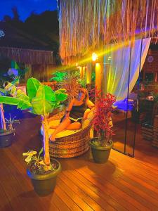 a woman sitting in a chair on a deck with plants at ॐ Rosa Astral ॐ in Praia do Rosa