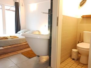 a bathroom with a tub and a toilet and a bed at Squat Deluxe Berlin, the hostel in Berlin