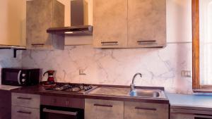 a kitchen with a sink and a stove top oven at PM Villa Arenosu Guest House in Fertilia