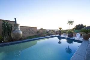 a swimming pool in a yard with white chairs and plants at Bay View Guest House in Somerset West