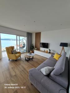 een woonkamer met een grijze bank en een gele stoel bij Penthouse Seaview in Trogir