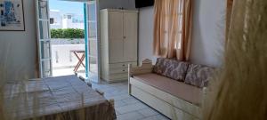 a bedroom with a couch and a window with a balcony at Golden Silence Studios in Agios Prokopios