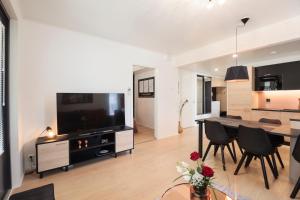 a living room with a dining table and a large screen tv at Apartment Tuomenkartano B1 iso huoneisto saunalla Kalajoki in Kalajoki