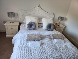 uma cama branca com almofadas e toalhas em Rothwell em Swansea