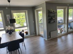 a dining room with a table and chairs and windows at Nydelig leilighet- Solrik/2 balkonger in Seim +14 photos